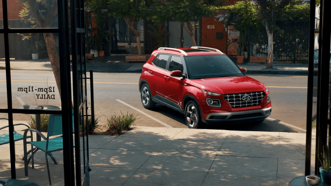 Hyundai Venue 2026 rojo estacionado calle SUV accesible más barato América vista lateral.