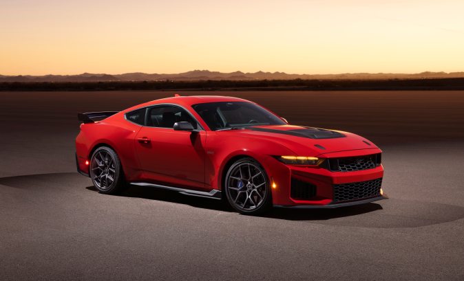 Ford Mustang Dark Horse SC rojo con paquete Track Pack, vista lateral al atardecer, alerón trasero y diseño aerodinámico, muscle car moderno de alto desempeño.