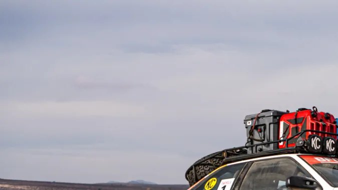 Toyota Corolla AWDROLA en rally safari off-road, levantando arena en desierto extremo.