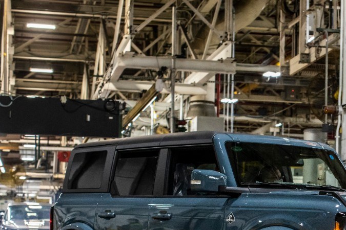 Ford Bronco azul en planta de producción, SUV todoterreno estacionado en fábrica de Ford, modelo 4 puertas con diseño robusto y preparación off-road