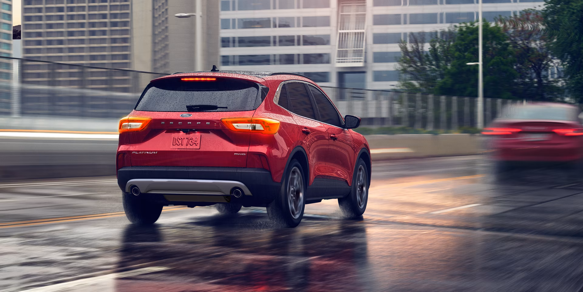 Ford Escape color rojo, modelo 2026 conduce a velocidad en la ciudad bajo la lluvia