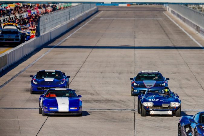 Desfile de Corvette Grand Sport de distintas generaciones en circuito Sebring, autos azules en formación, homenaje histórico a la leyenda deportiva de Chevrolet.