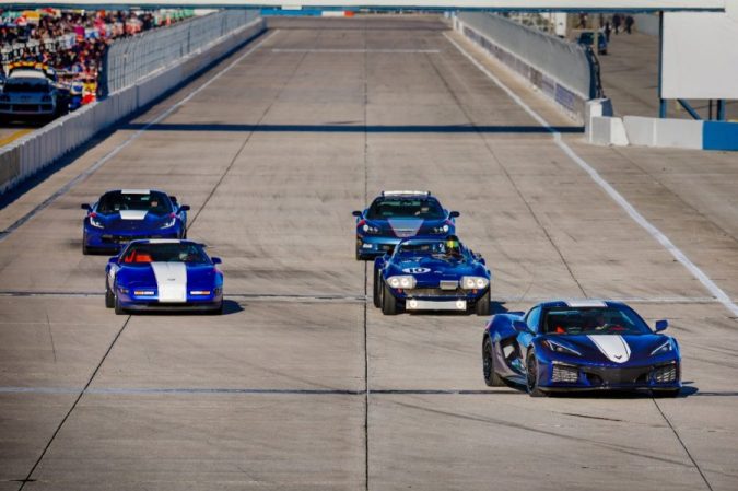 Desfile de Corvette Grand Sport de distintas generaciones en circuito Sebring, autos azules en formación, homenaje histórico a la leyenda deportiva de Chevrolet.