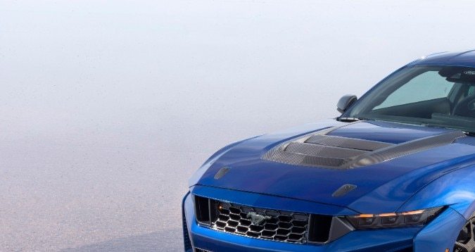 Ford Mustang Dark Horse SC Track Pack azul en ángulo tres cuartos frontal, carrocería ensanchada, cofre de fibra de carbono y rines deportivos listos para circuito.