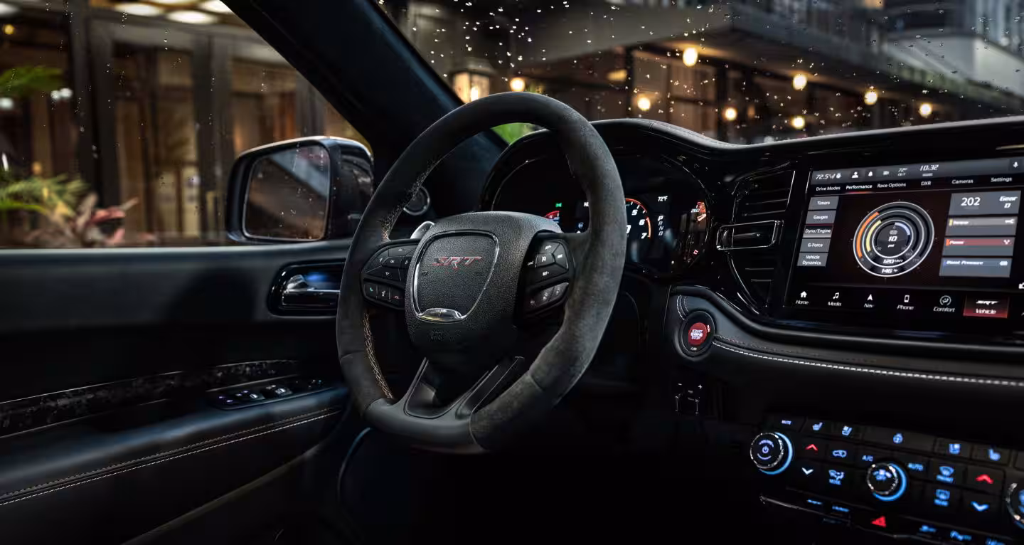 Interior Dodge Durango SRT 2026 con volante deportivo, pantalla Uconnect y cabina tecnológica, mostrando lujo, enfoque en desempeño y experiencia de manejo para conductor.