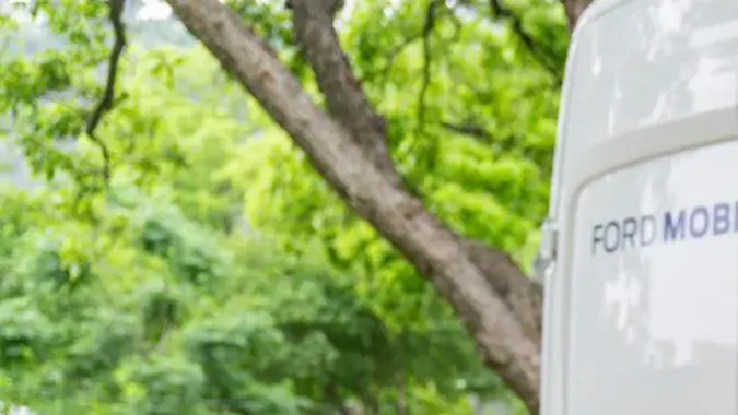 Técnico Ford Mobile Service repara motor F-150 con laptop junto a camioneta, servicio rápido a domicilio.