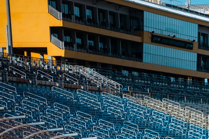 Vista panorámica Homestead-Miami Speedway: graderías vacías, torres luces y pista ovalada con autos en acción. Circuito NASCAR Florida.