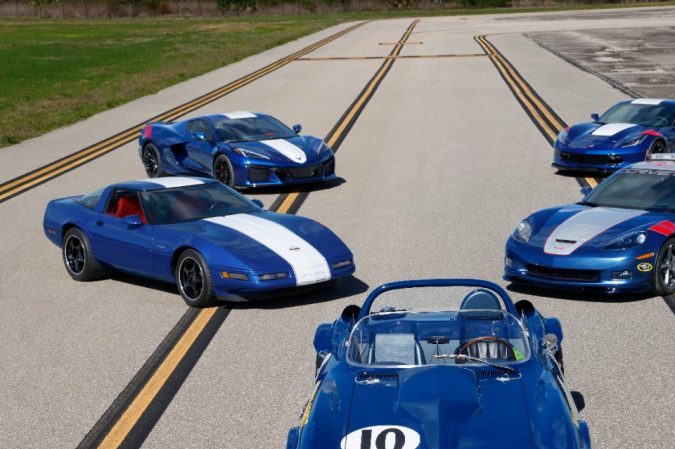 Cinco Corvette Grand Sport azules de varias generaciones estacionados en pista, vista frontal, énfasis en evolución de diseño y tradición de autos deportivos Chevrolet.
