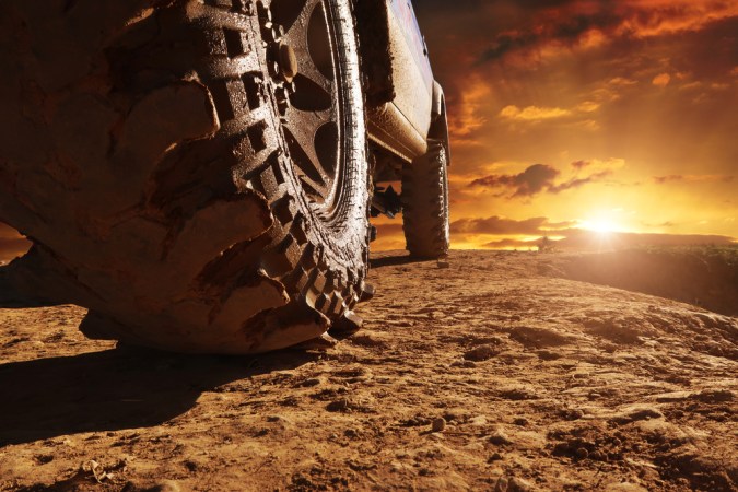Cierre de una rueda de coche en barro en un camino de tierra contra un cielo con puesta de sol