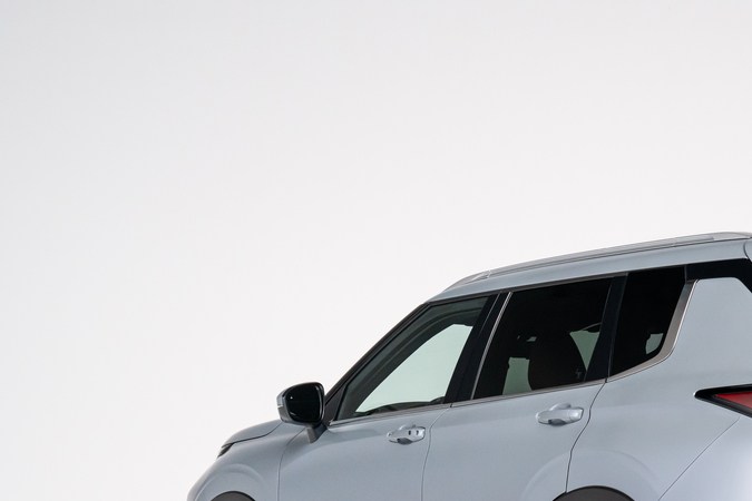 Vista trasera tres cuartos del Mitsubishi Outlander 2026 gris, SUV híbrido enchufable con rines grandes y diseño aerodinámico para ciudad y carretera