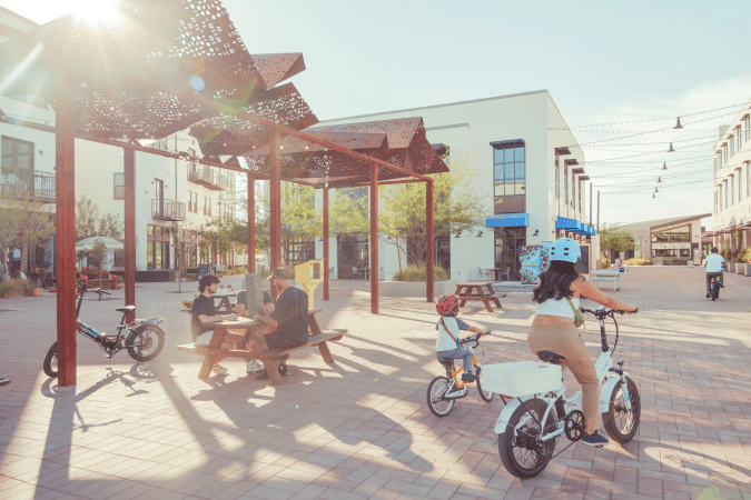 Personas en bicicletas en patio de Culdesac Tempe, vida peatonal en zona prohibida para autos.