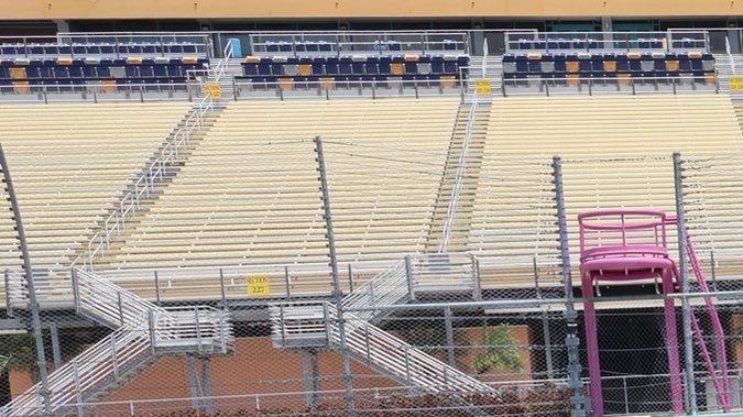 Homestead-Miami Speedway con grupo diverso en uniformes rosados y verde junto a auto Ford Mustang tropical. Día de prensa NASCAR Miami.