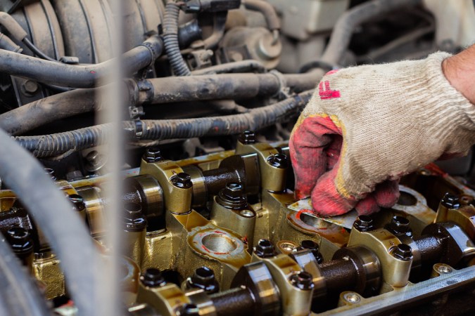 Mecánico realizando reparación de junta de culata en motor de auto, proceso de cambio y mantenimiento del sistema de culata.