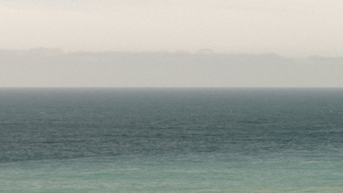 Rivian R2 2027 junto a R1S en costa, SUVs eléctricos off-road de alta potencia y diseño robusto.