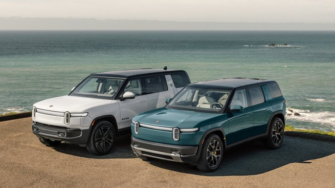 Rivian R2 2027 junto a R1S en costa, SUVs eléctricos off-road de alta potencia y diseño robusto.
