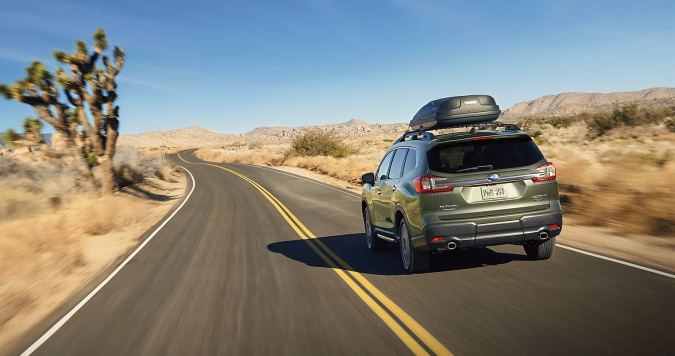 Subaru Ascent 2026 verde conduciendo por carretera curva en desierto con portaequipajes en el techo