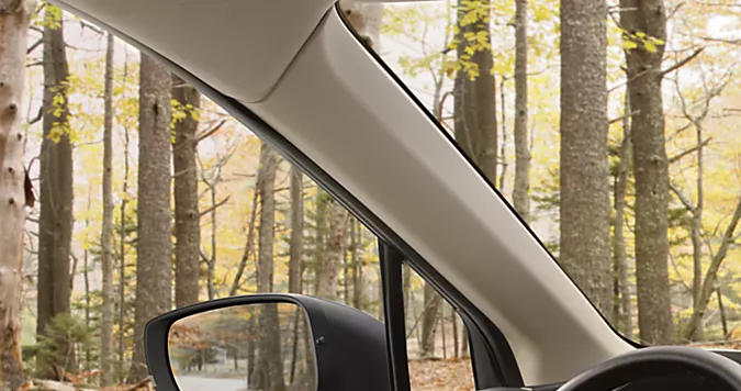 Interior del Subaru Ascent 2026 con asientos en cuero marrón, pantalla táctil y vista panorámica a bosque otoñal