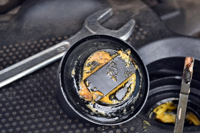 Aceite de motor con aspecto lechoso en tapa y varilla, síntoma de junta de culata dañada o mezcla de refrigerante con aceite.