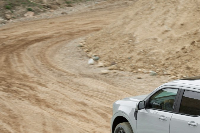 Ford Maverick Tremor 2023 circulando en pista de tierra con motocicleta en la caja, pickup compacta off-road en acción