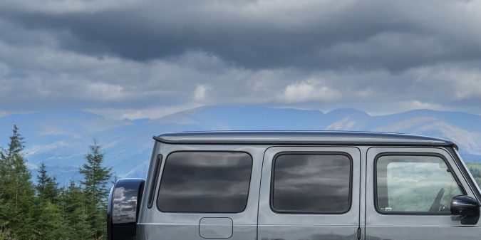 Vista lateral del icónico SUV de lujo Mercedes G-Wagon en paisaje montañoso con ruedas de alto rendimiento.
