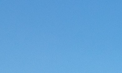 Dos Subaru Outback Wilderness, verde y azul, estacionados en un paisaje rocoso y árido con montañas al fondo.