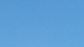 Dos Subaru Outback Wilderness, verde y azul, estacionados en un paisaje rocoso y árido con montañas al fondo.