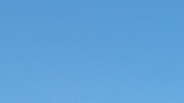 Dos Subaru Outback Wilderness, verde y azul, estacionados en un paisaje rocoso y árido con montañas al fondo.