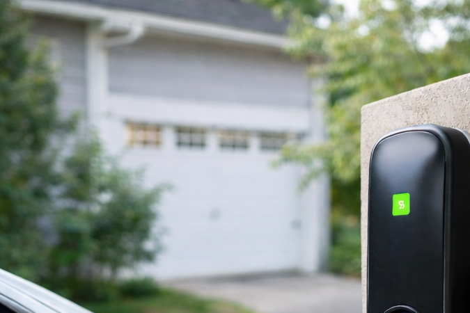 Electricista profesional instalando cargador de pared para coche eléctrico en casa.