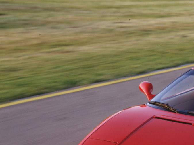 Ferrari F355 rojo en movimiento sobre pista, deportivo clásico italiano con diseño aerodinámico y estilo noventero