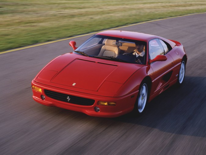 Ferrari F355 rojo en movimiento sobre pista, deportivo clásico italiano con diseño aerodinámico y estilo noventero
