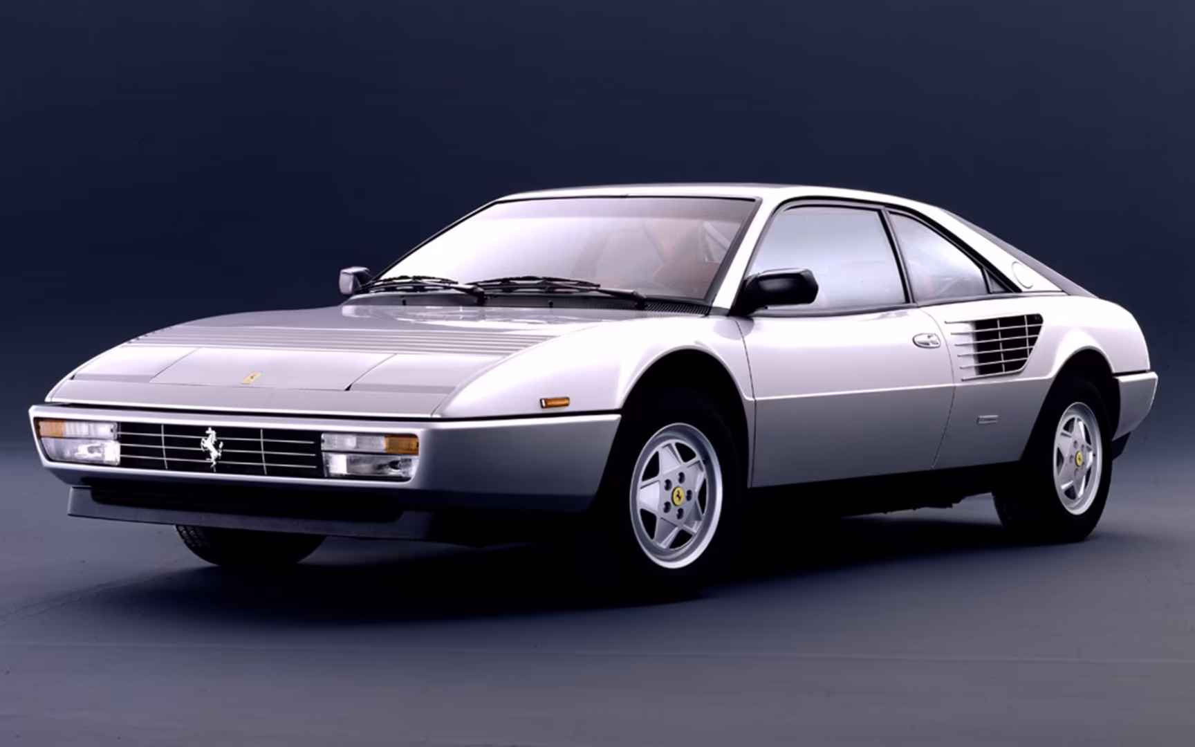 Ferrari Mondial plateado en estudio, coupé clásico italiano con líneas elegantes, motor central y diseño vintage