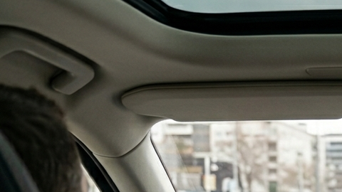 Conductor en un Volvo XC90 con una pequeña pantalla central de Android Automotive y panel de madera.