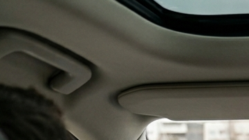 Conductor en un Volvo XC90 con una pequeña pantalla central de Android Automotive y panel de madera.