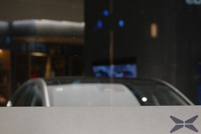 primer plano del logo de Xpeng Motors en el cristal de la tienda. Difumina el coche eléctrico dentro de la tienda. Xpeng es una empresa china de vehículos eléctricos