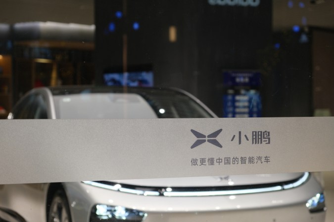 primer plano del logo de Xpeng Motors en el cristal de la tienda. Difumina el coche eléctrico dentro de la tienda. Xpeng es una empresa china de vehículos eléctricos