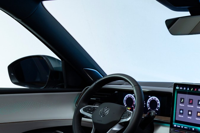 Interior VW Atlas 2027 R-Line: tablero moderno con pantalla grande, iluminación ambiental y consola central en tonos claros.