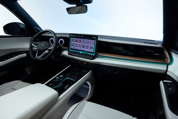 Interior VW Atlas 2027 R-Line: tablero moderno con pantalla grande, iluminación ambiental y consola central en tonos claros.