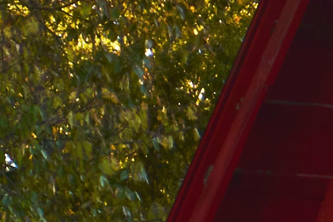 Scout Terra pick-up eléctrica gris con granero rojo de fondo, vista trasera con luces LED encendidas.