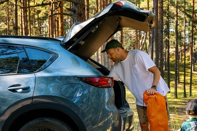 familia con niños retire los suministros de camping del maletero del coche en el bosque. vacaciones de verano, viaje por carretera