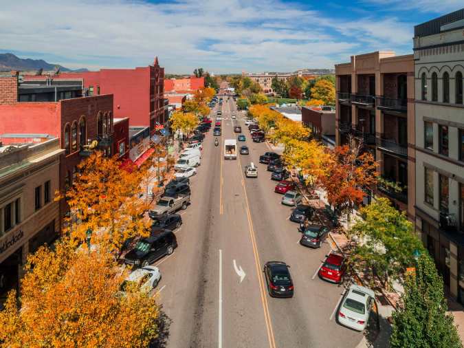 Paisaje urbano de calles en Colorado otoñal con árboles amarillos y tráfico, contexto para nuevo sistema de multas por exceso de velocidad