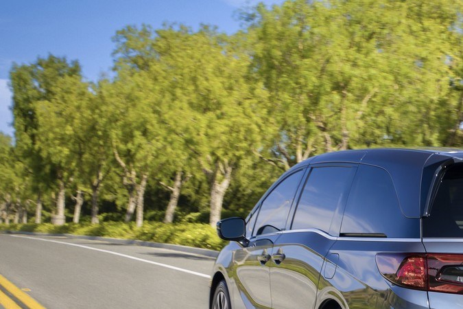 Honda Odyssey gris 2025 manejando en carretera - Vista trasera de la minivan familiar