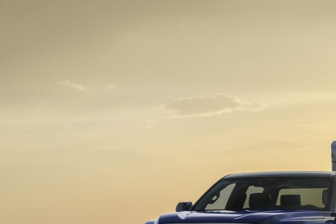 Toyota Tundra 2024 Platinum azul remolcando tráiler Toyota Racing al atardecer, demostrando capacidad de remolque, estabilidad y desempeño para trabajo y aventura.