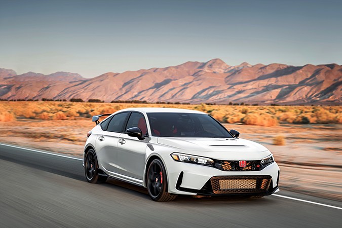 Honda Civic Type R 2025 blanco circulando en carretera desértica, con diseño deportivo, alerón trasero y llantas de alto rendimiento.