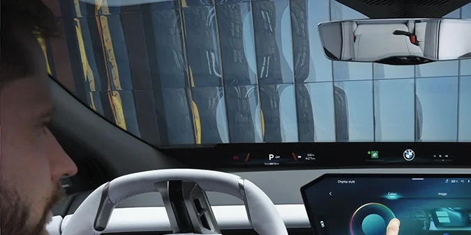 Interior BMW iX3 50: conductor usando la gran pantalla táctil en el moderno cockpit del SUV eléctrico premium.