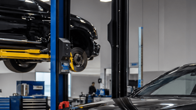 Mercedes-Benz negro en taller de blindaje, técnico trabajando en puerta desmontada para instalar protección balística y reforzar carrocería