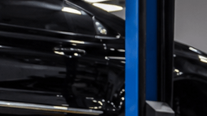 Mercedes-Benz negro en taller de blindaje, técnico trabajando en puerta desmontada para instalar protección balística y reforzar carrocería