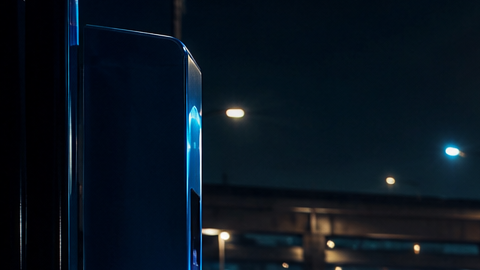 Auto eléctrico cargándose de noche con cable de luz azul e impuestos al fondo