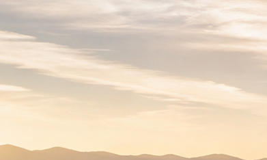 Grupo de autos híbridos deportivos y familiares, incluyendo Ferrari, Corvette, McLaren, BMW y Toyota Prius, estacionados en mirador de montaña al atardecer.