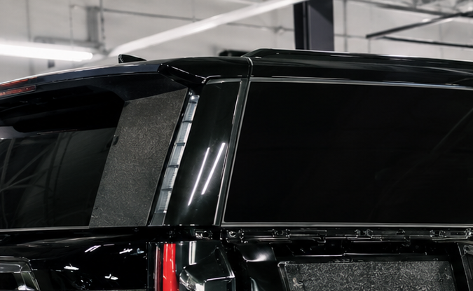 Técnicos instalando blindaje y vidrio antibalas en camioneta SUV negra dentro de taller especializado en armoring en Estados Unidos.