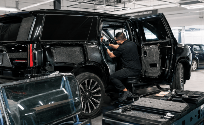 Técnicos instalando blindaje y vidrio antibalas en camioneta SUV negra dentro de taller especializado en armoring en Estados Unidos.